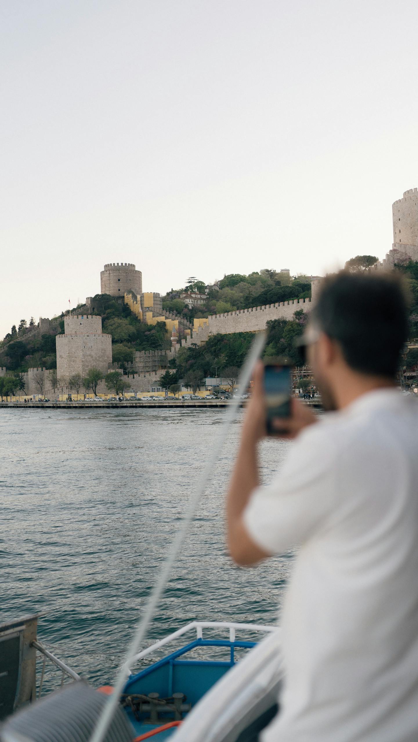 A man taking a picture of a castle on a boat