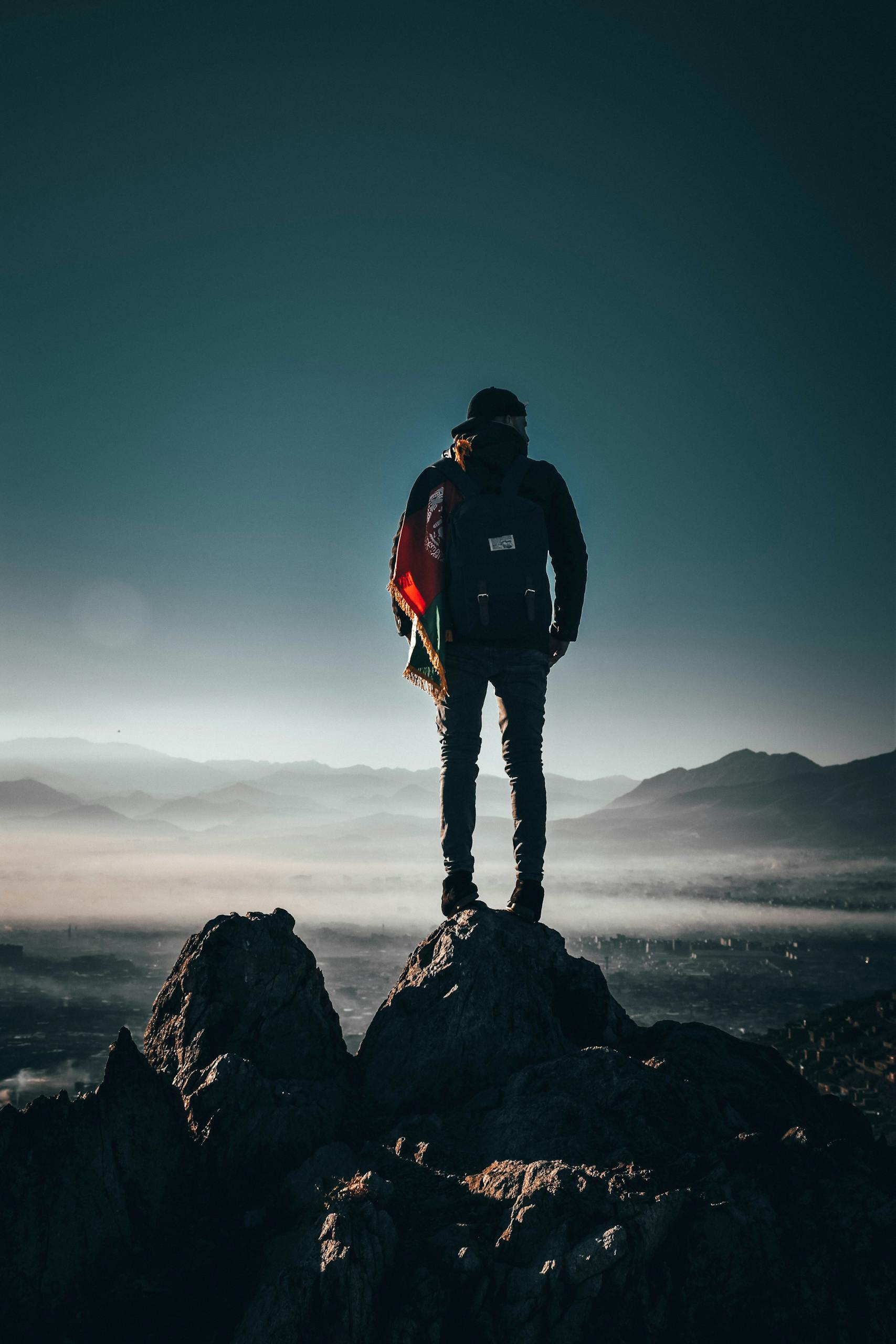 Man Carrying Backpack Standing on Rock Formation